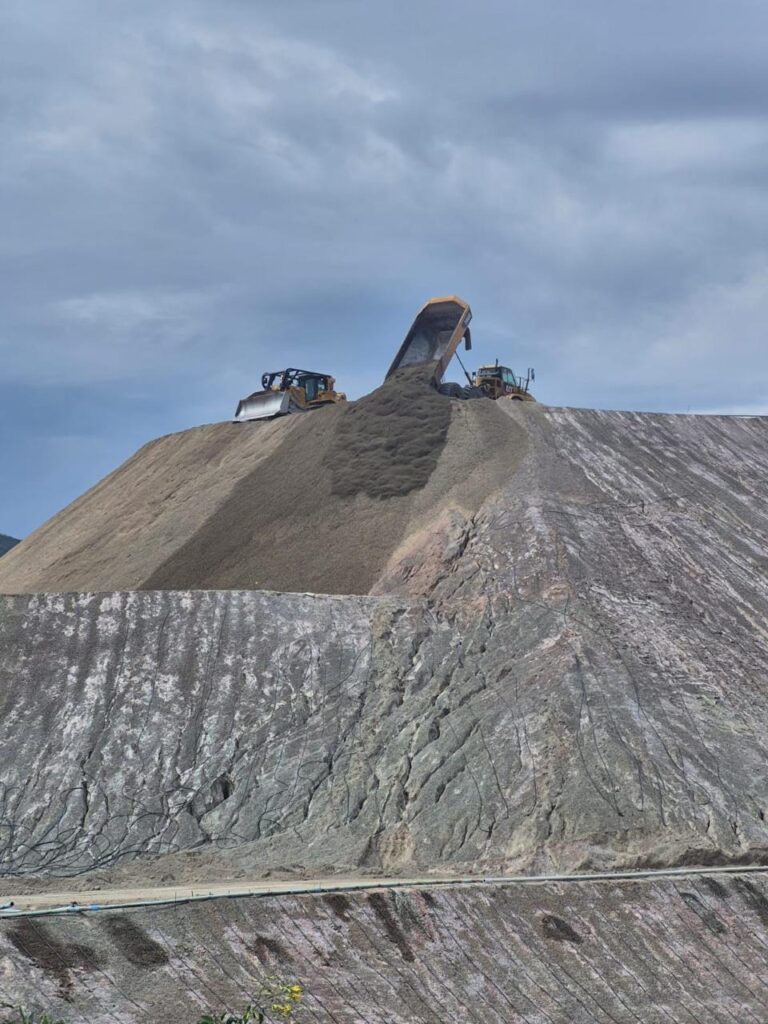 Camión descargando material junto a maquinaria sobre un terraplén.