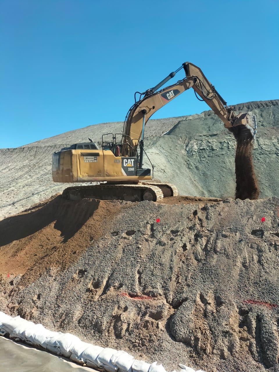 Excavadora CAT trabajando sobre un talud de material.